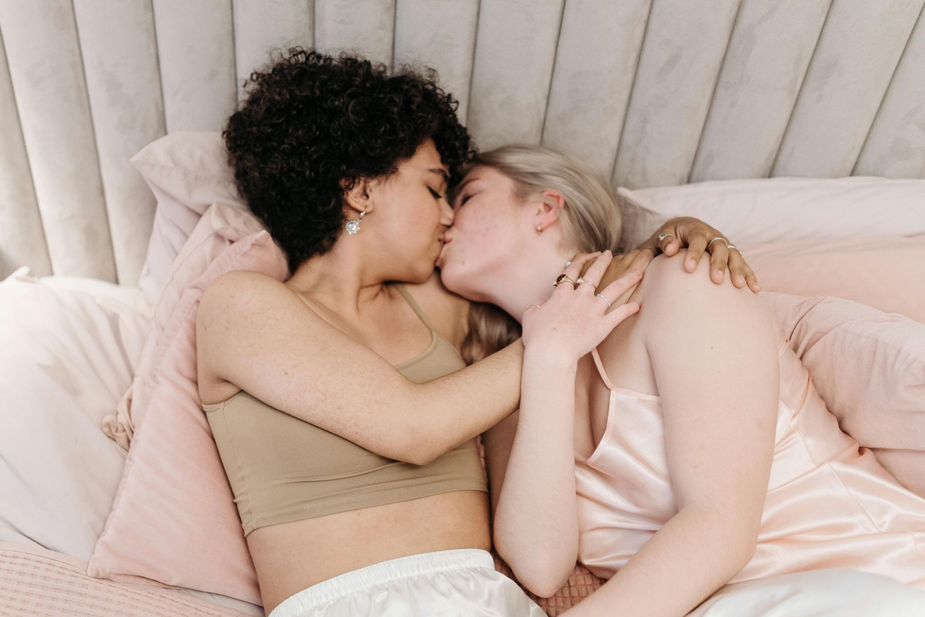 Two lesbian women in a bed kissing each other.