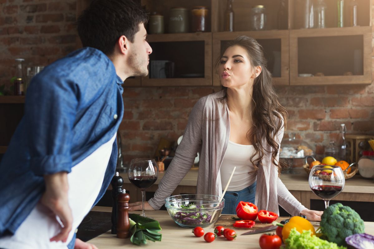 Man and woman cooking together and blowing a kiss towards each other